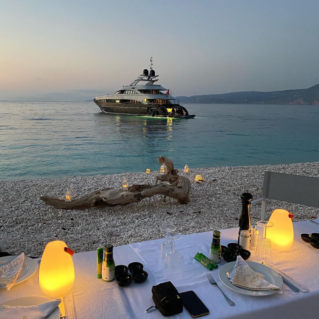 dining on the beach with yacht in the distance