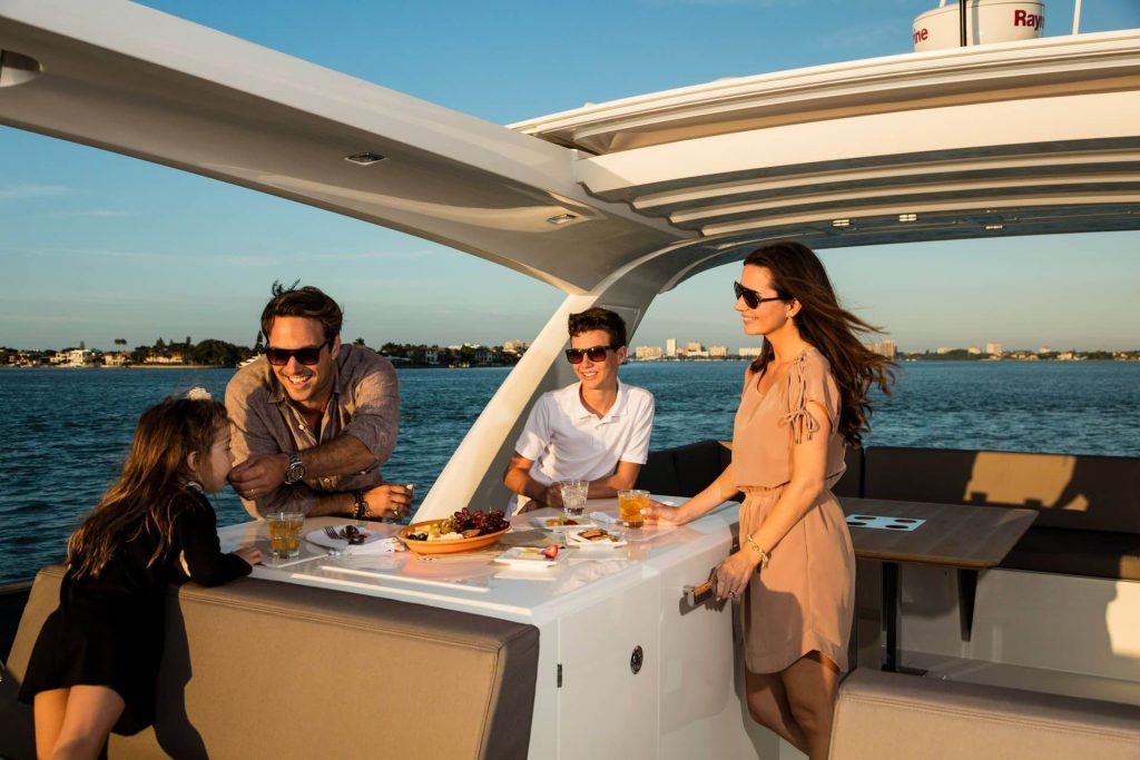 family on a main yacht deck talking around a table