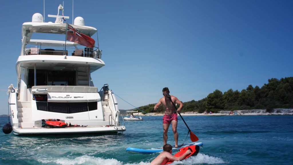 two people having a fun with water toys near yacht