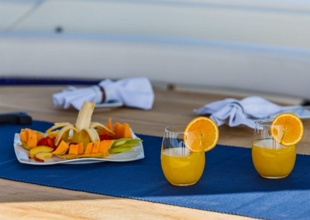 two glasses of an orange juice served with banana on a plate