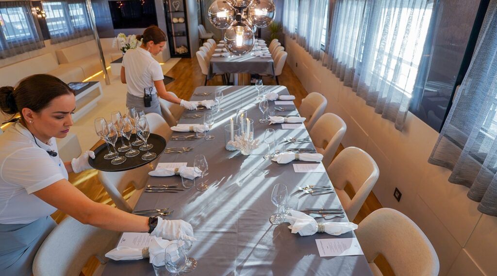 2 crew members decorating a dining table onboard a freedom yacht charter