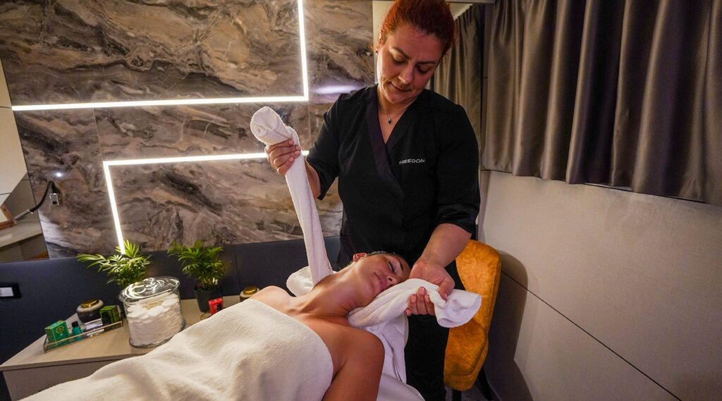 crew member massaging a charter guests onboard freedom yacht