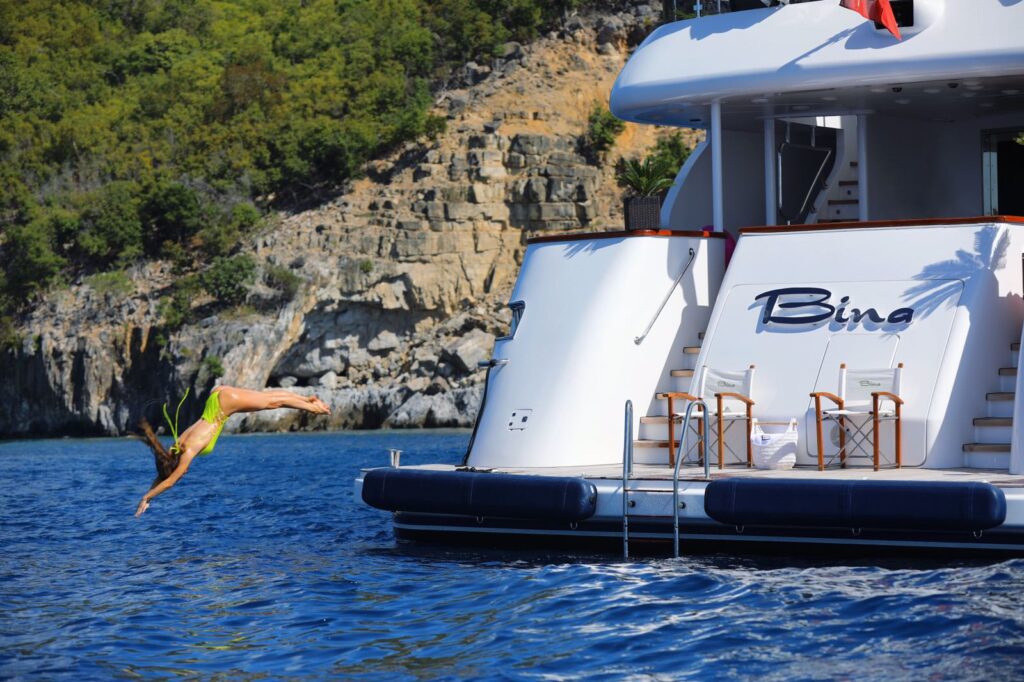 lady jumping in the sea from the bina yacht swimming platform